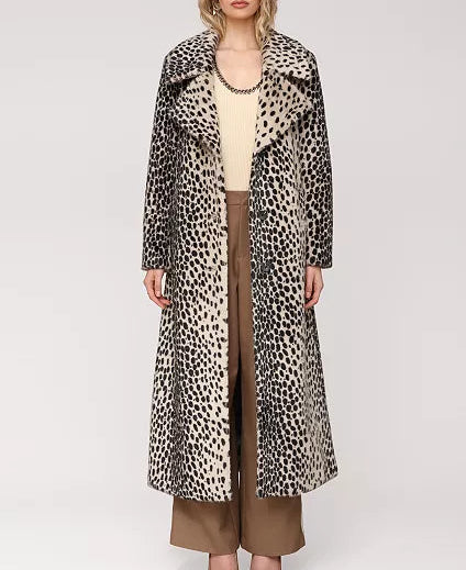 A model stands against a light gray studio background wearing a long leopard-print coat over a cream top and brown wide-leg pants.