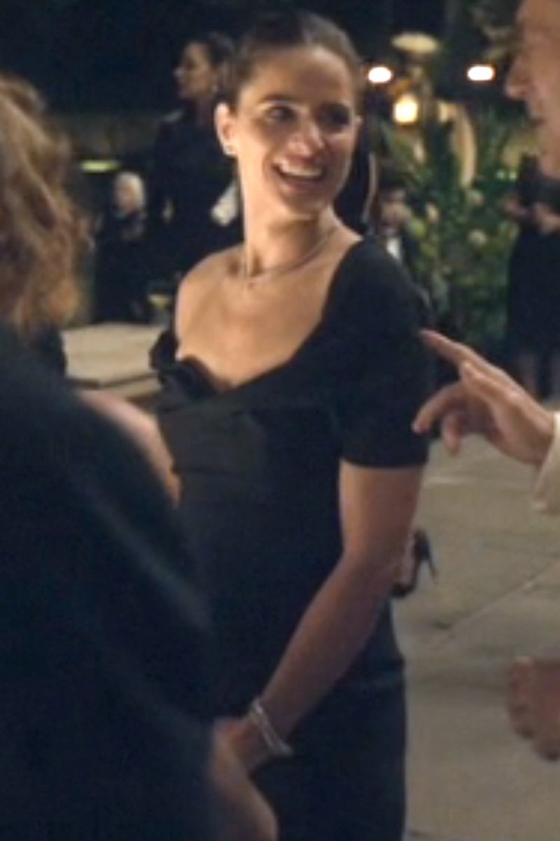Woman in a black dress smiling outdoors with blurred background