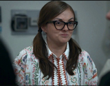 Woman wearing glasses and a patterned shirt in an indoor setting
