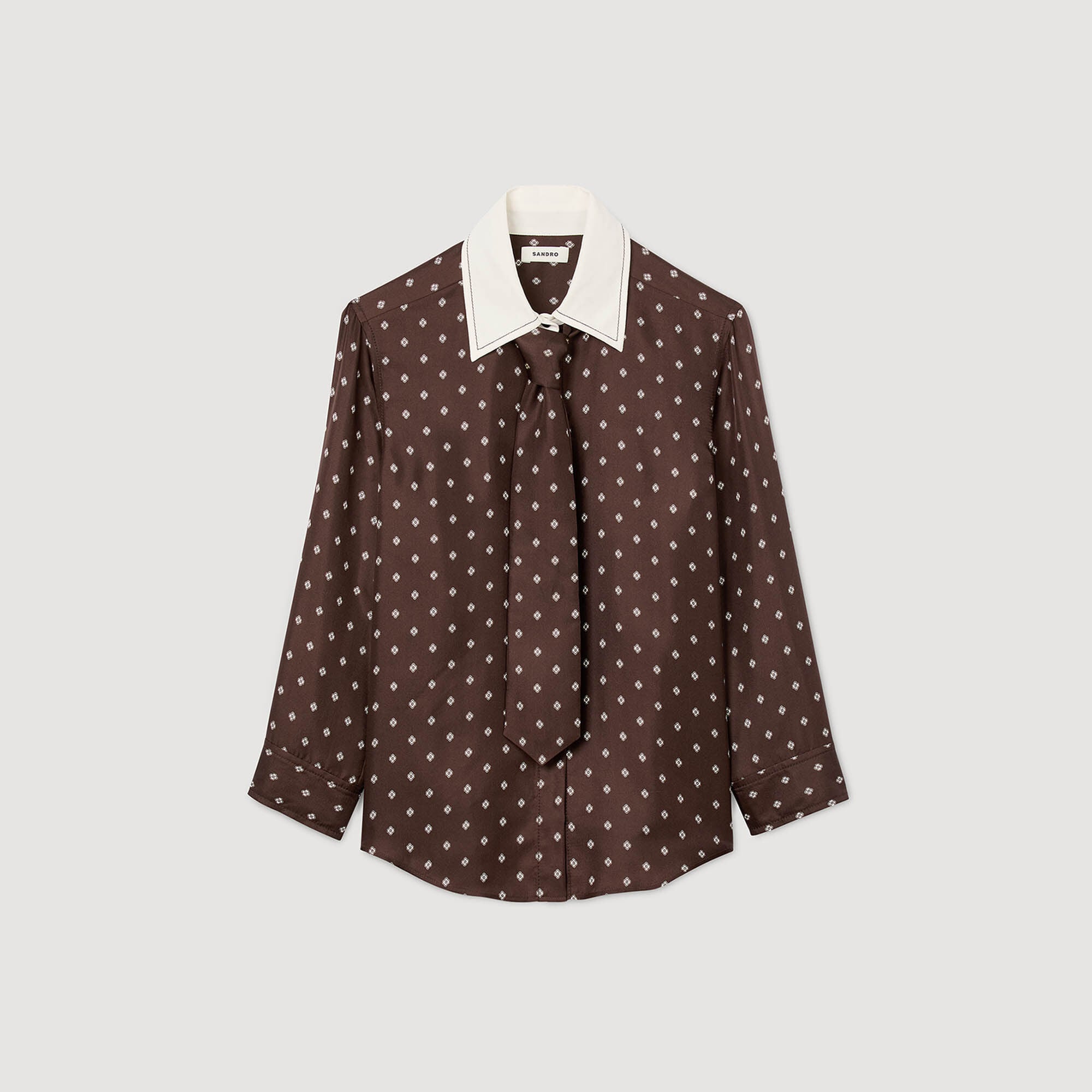 Brown polka dot blouse with white collar on a light gray background
