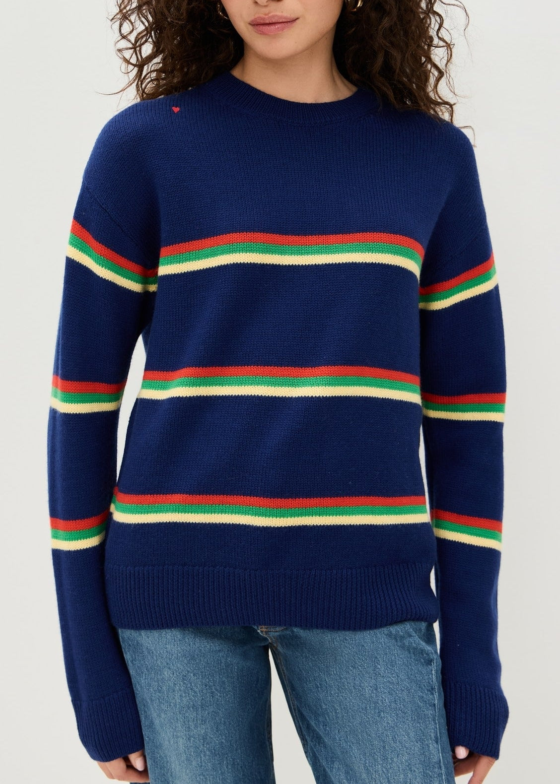 Woman wearing a navy sweater with colorful stripes on a white background