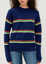Woman wearing a navy sweater with colorful stripes on a white background