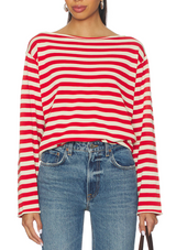 Person wearing a red and white striped long-sleeve top with blue jeans on a white background