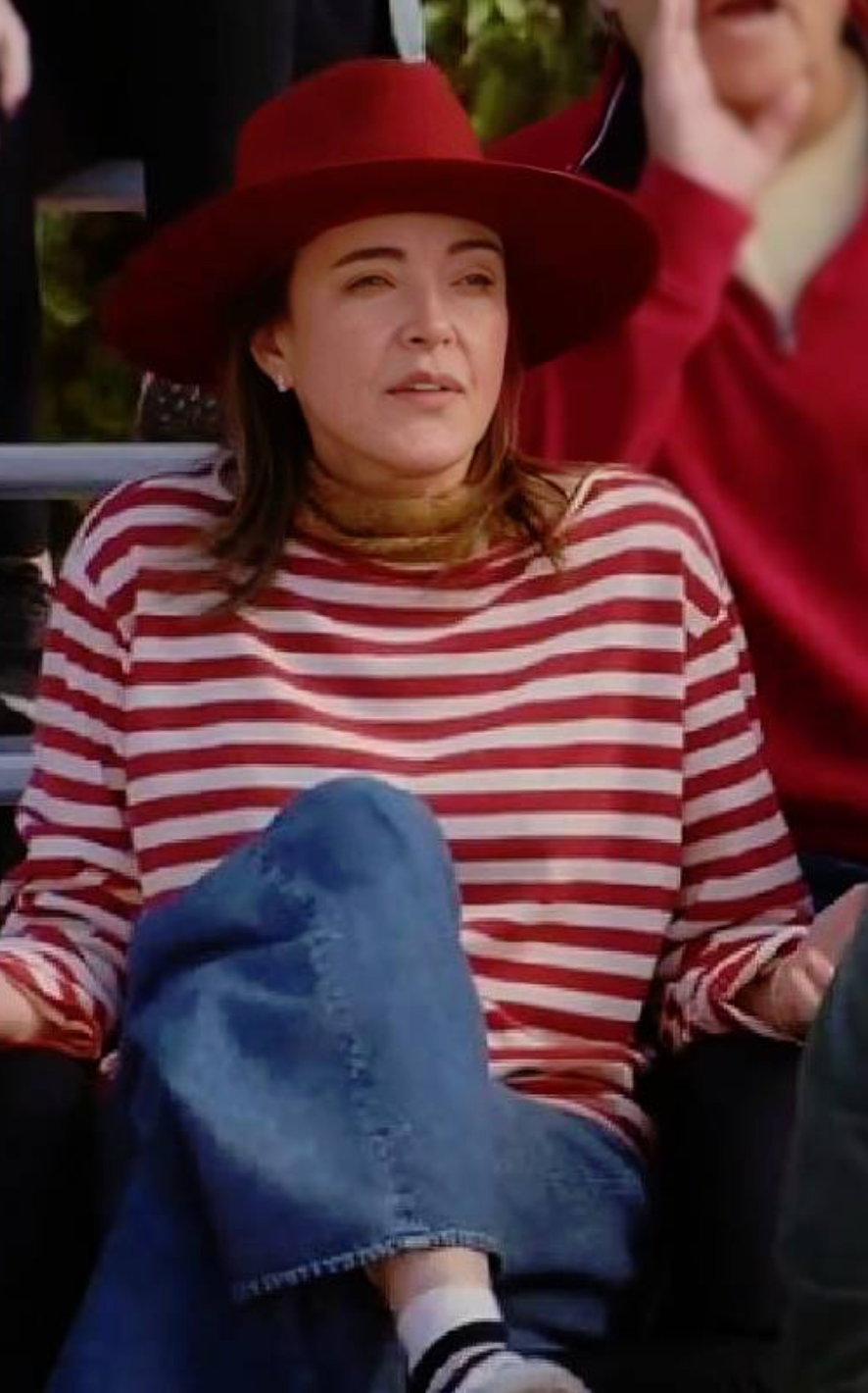 Person wearing a red and white striped shirt and blue jeans, sitting outdoors.