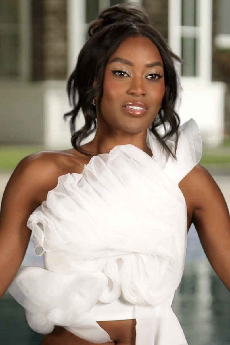 Woman wearing a white dress with ruffled details outdoors.