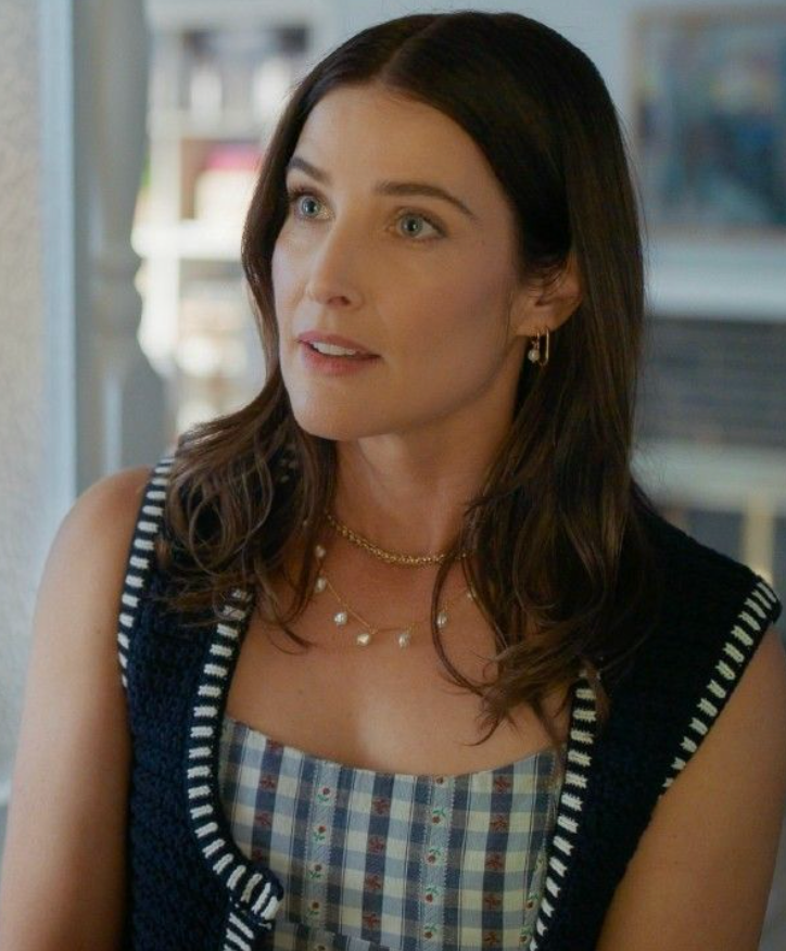 Woman wearing a checkered dress with a black cardigan in an indoor setting