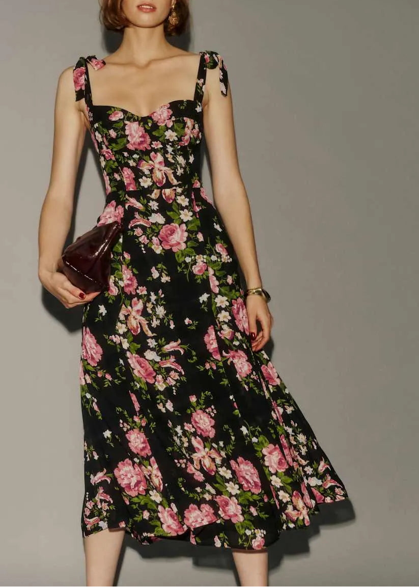 Woman wearing a black floral dress against a gray background