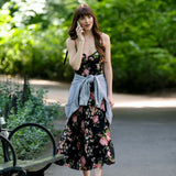 Woman in a floral dress talking on a phone in a park