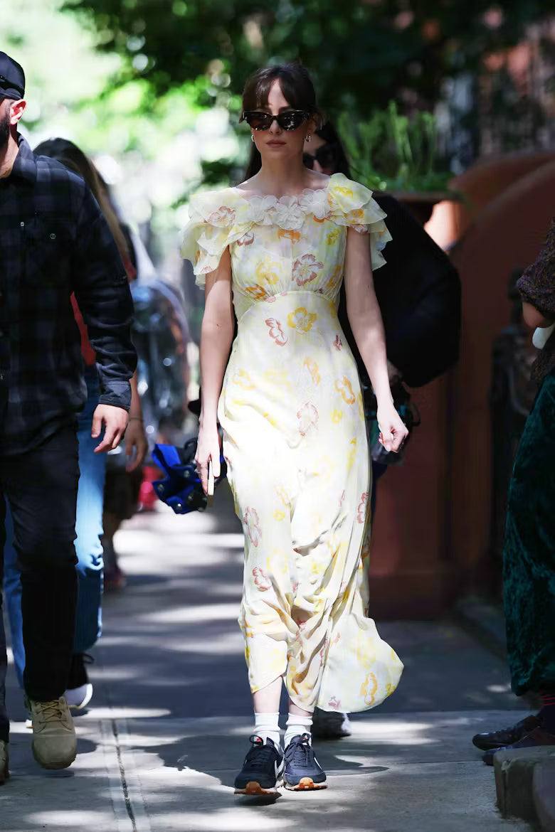 Woman in a floral dress walking outdoors with people around