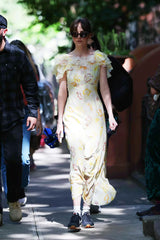 Woman in a floral dress walking outdoors with people around