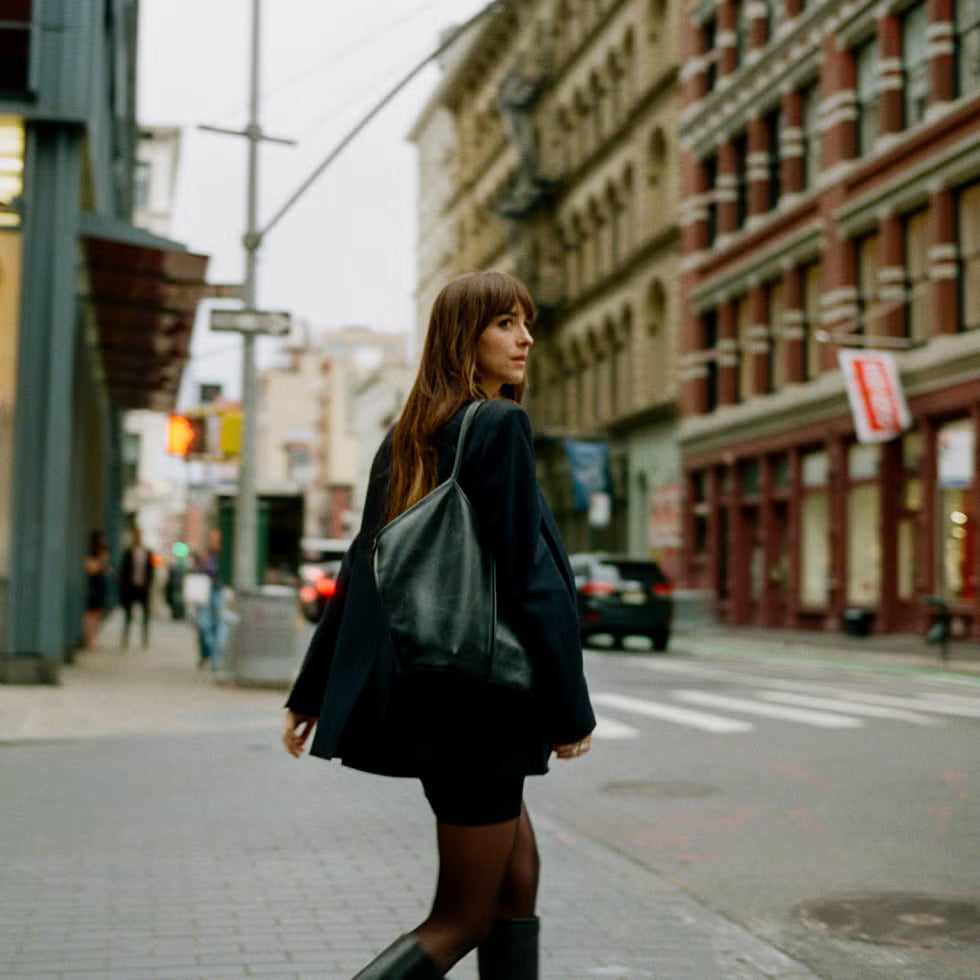 Woman walking on a city street with buildings and traffic lights in the background
