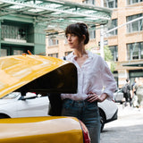 Woman standing next to a yellow car with a cityscape background