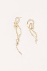 Gold earrings on a light beige background