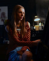 Woman sitting in a dimly lit room with a lamp in the background