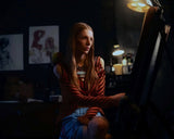 Two people standing close together with a warm light source in the background