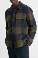 Person wearing a plaid shirt with green and blue checkered pattern on a white background