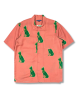 Coral shirt with green dog pattern on a white background