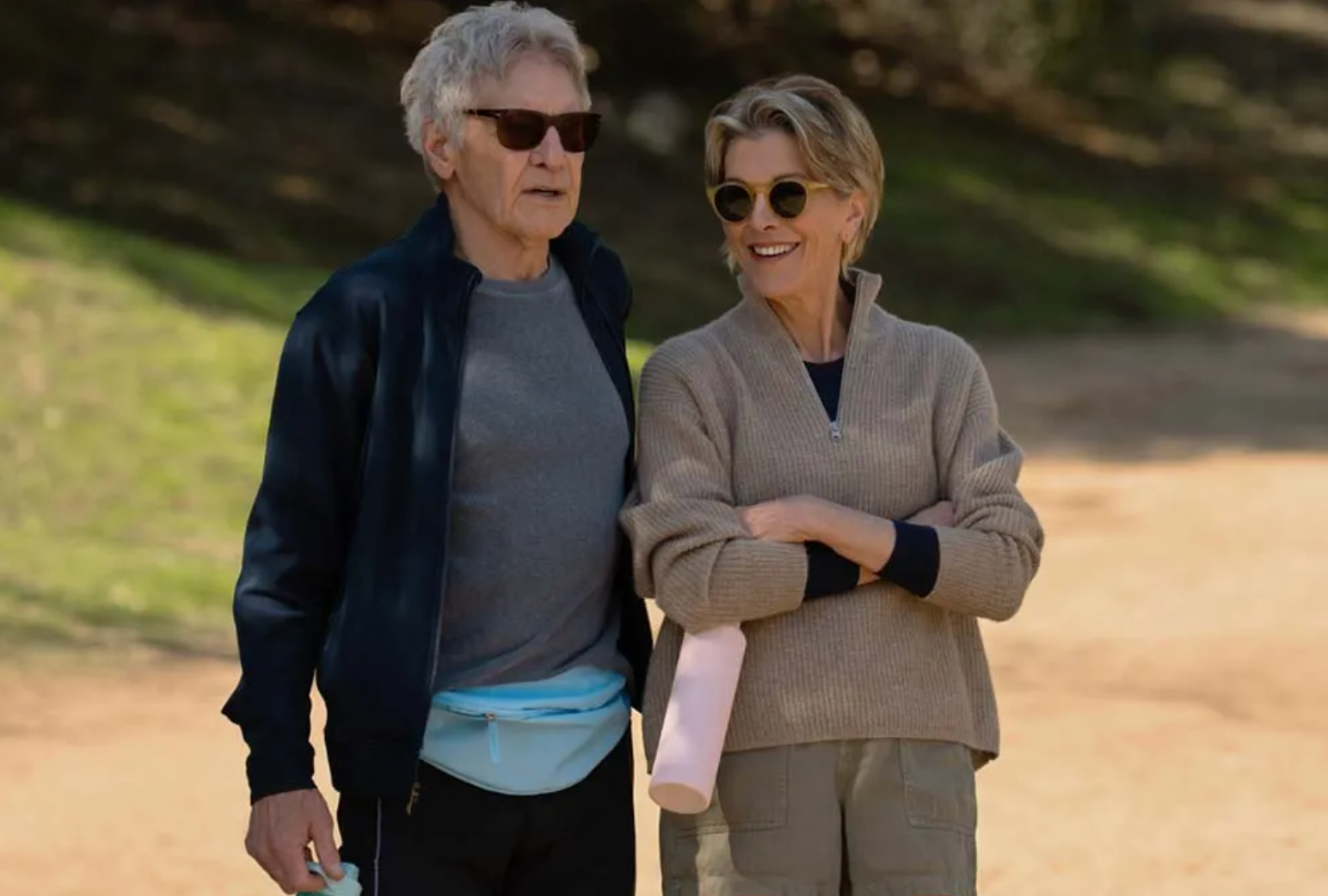 Two people walking outdoors on a path with greenery in the background