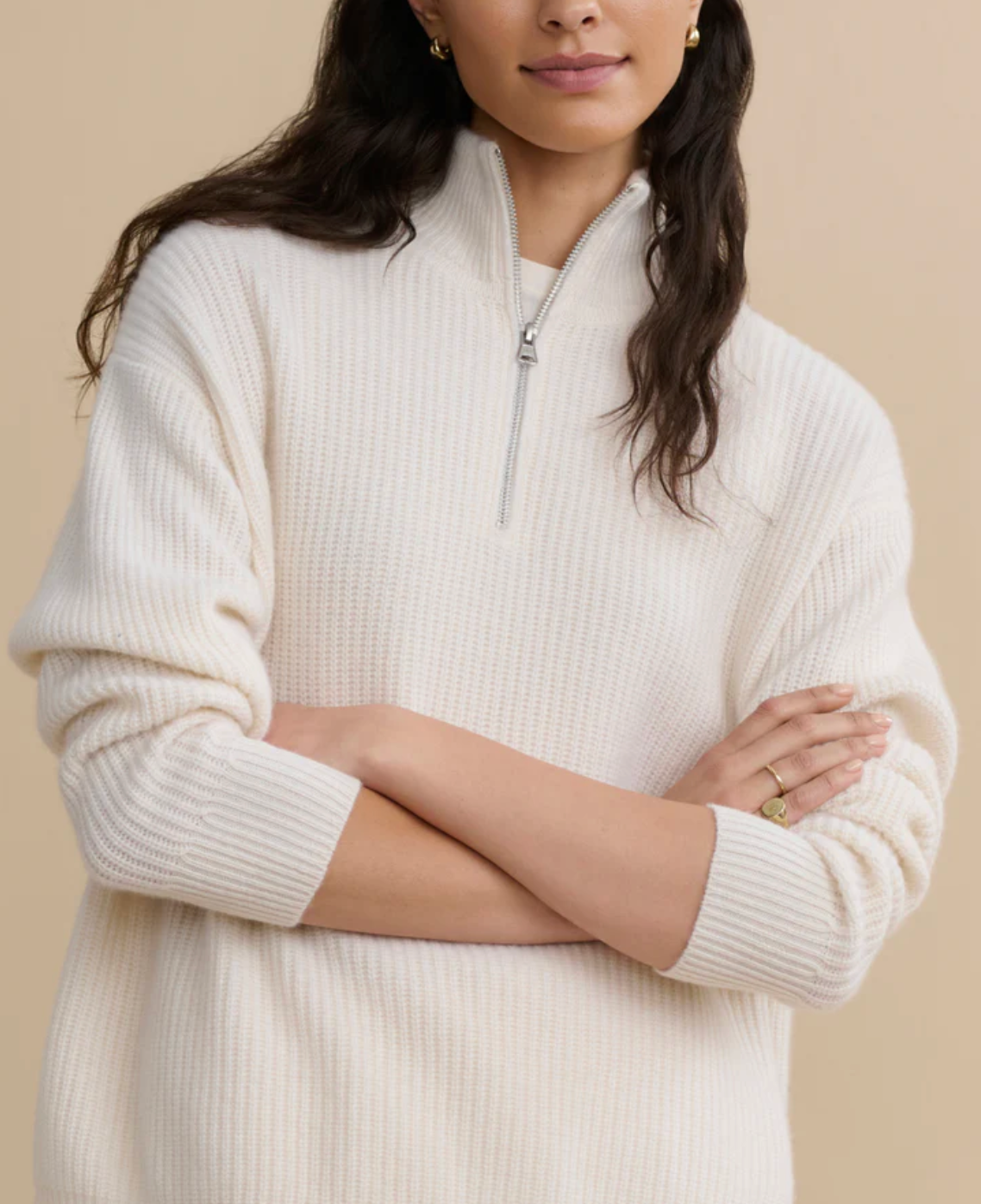 Woman wearing a cream-colored half-zip sweater against a beige background