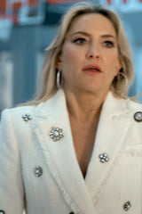 Woman wearing a white coat with decorative buttons and brooches.