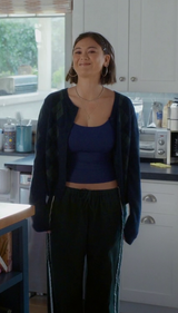Woman standing in a kitchen wearing a dark blue top and black cardigan.