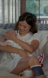 Woman holding a baby on a couch with a cup in her hand
