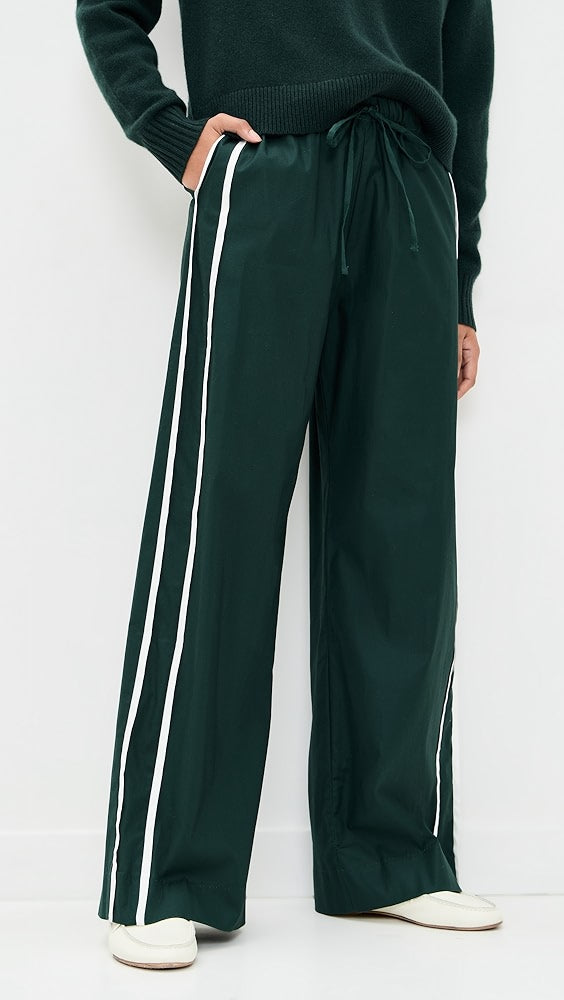 Green track pants with white stripes on a plain background