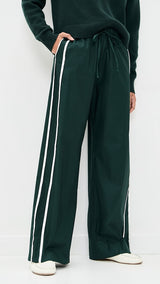 Green track pants with white stripes on a plain background