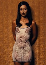 Woman wearing a patterned dress against a textured wall.