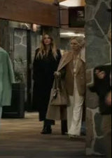 People walking in a modern indoor setting with a stone wall and large windows.