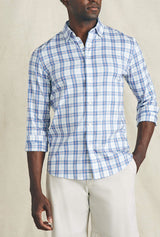 Man wearing a blue and white checkered shirt with rolled-up sleeves against a beige background