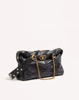 Black handbag with gold chain and logo on a light beige background